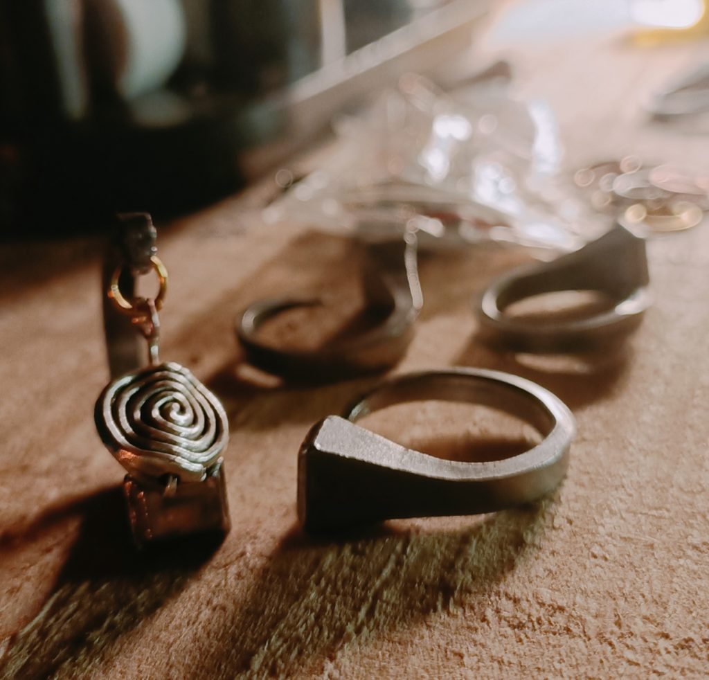 horseshoe nail jewellery laying on a wooden slab in the evening light