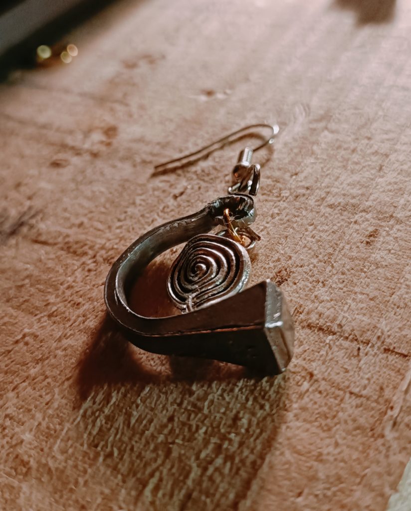 curved horseshoe nail earring with silver spiral in middle